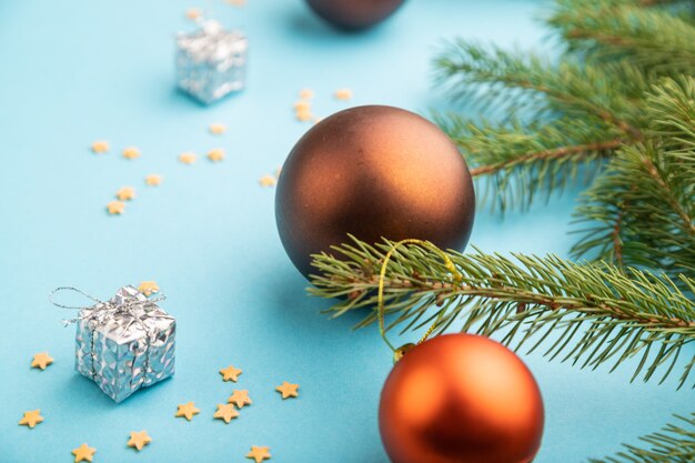 Christmas composition. Decorations, bronze balls, fir and spruce branches on blue paper.