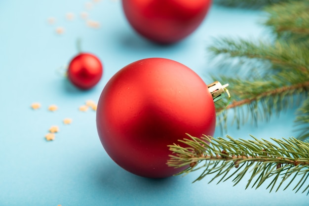 Composizione di natale. decorazioni, palline rosse, rami di abete e abete rosso su carta blu.