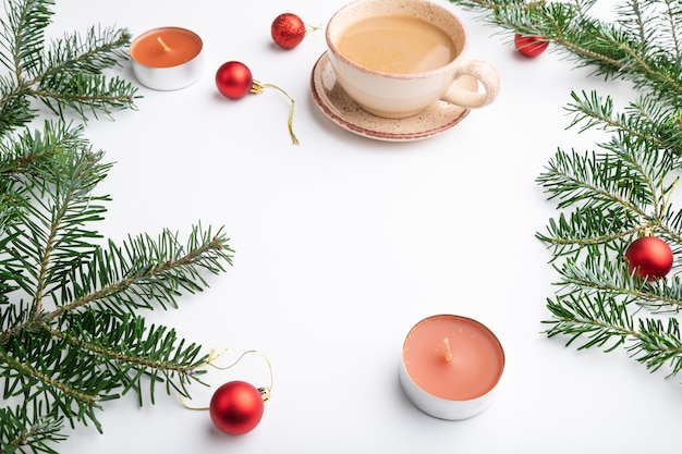 Christmas or composition. Decorations, red balls, fir and spruce branches, cup of coffee, candles on white paper