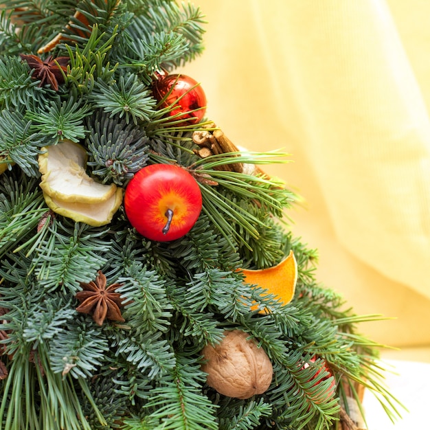 전나무 나무 가지, 오렌지와 사과 조각, 호두, 아니스와 공의 크리스마스 구성. 샷을 닫습니다. 복사 공간이 있는 노란색 배경에