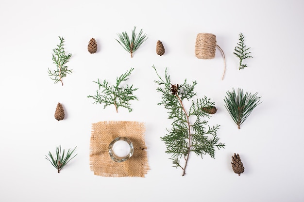 Composizione di natale. regalo, decorazioni natalizie, rami di cipresso, pigne su bianco