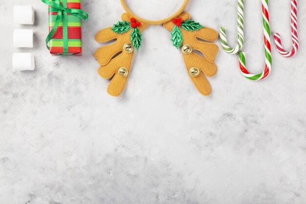 Christmas composition. Gifts, caramel cane, marshmellow, headband antlers on gray concrete background. Top view. Copy space