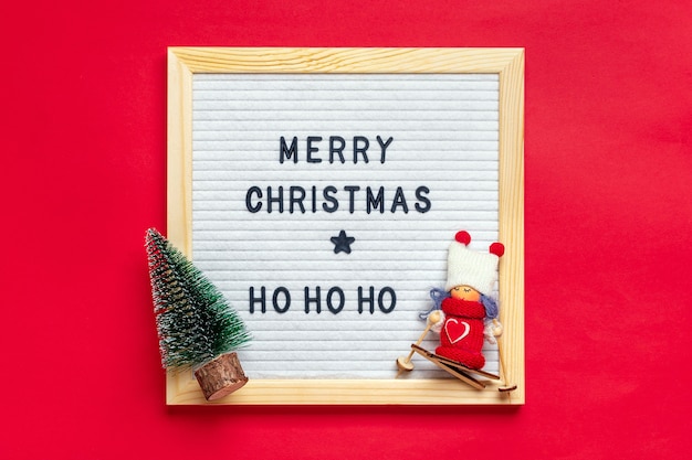 Christmas composition of girl skier, tree, white felt board on red background