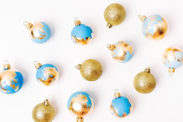 Christmas composition made of blue  Christmas balls with gold leaf on white background. Flat lay, top view