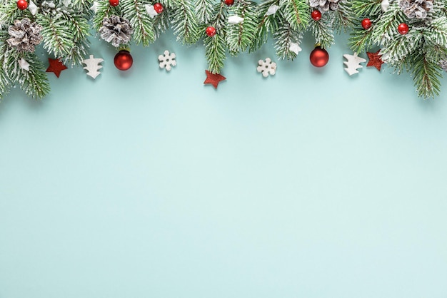 モミの木の枝、休日の装飾、青い背景に赤いベリーで作られたクリスマスの構成。フラットレイ