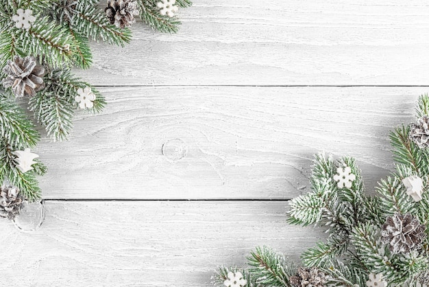 白い木製の背景にモミの木のお祝いの銀の装飾で作られたクリスマスコンポジションフラットレイ