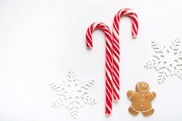 Christmas composition made of snowflakes gingerbread man cookies and candy on white background. Winter holidays concept. Flat lay, top view, copy space