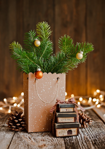 Christmas composition. Paper bag with and bumps fir branches brown wooden background and bokeh lights.