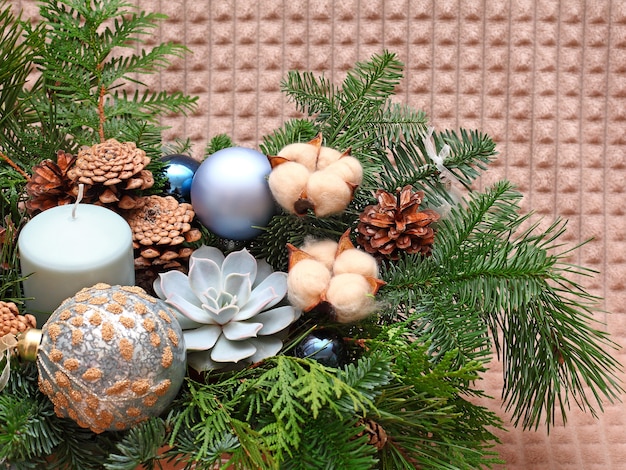 Christmas composition of pine branches, cones, cotton, balls and candle. Close up shot. On beige background