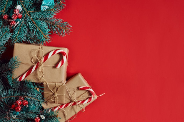 Christmas composition of pine cones spruce branches and stack of gift boxes on red background