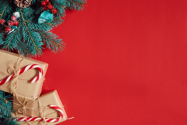 Christmas composition of pine cones spruce branches and stack of gift boxes on red background