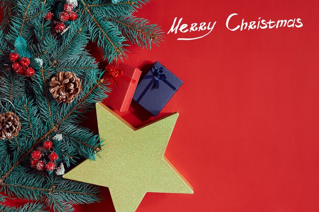 Christmas composition of pine cones spruce branches and stack of gift boxes on red background