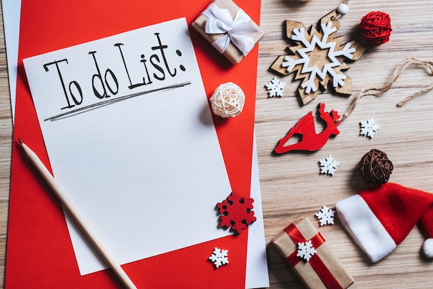 Composizione natalizia di decorazioni per alberi di pino e confezioni regalo con pezzo di carta bianco con lista delle cose da fare