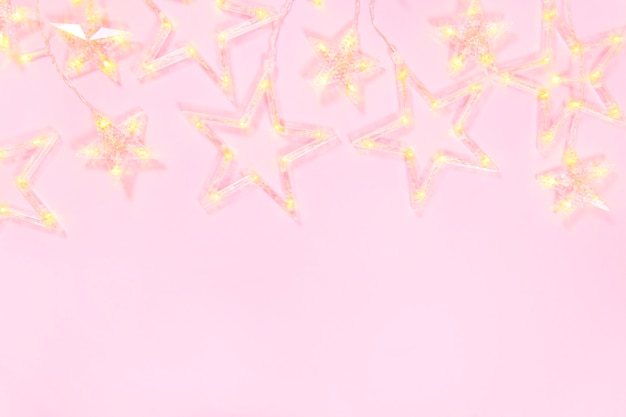 Christmas composition on a pink background. Frame of garland star. Christmas concept. Flat lay, top view and copy space