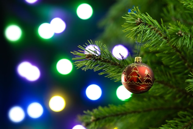 Foto composizione natalizia palla rossa su un albero di natale in primo piano su uno sfondo scintillante