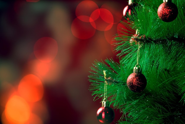 Foto composizione natalizia palle rosse su un albero di natale su uno sfondo rosso con bokeh