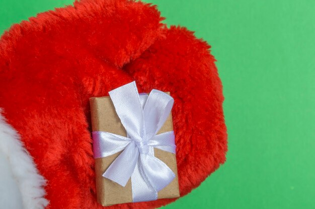 Christmas composition red fur mitten of santa claus with gifts on a green background. Template for postcards, packaging.Close-up