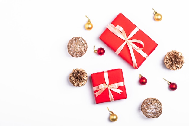 크리스마스 구성입니다. 흰색 배경에 빨간색 선물 상자, 소나무 콘, 금색 및 빨간색 장식 장식. 겨울 휴가 개념입니다. 상위 뷰 복사 공간