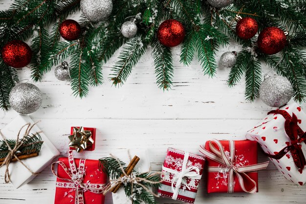 Photo christmas composition of red gift boxes and fir tree branches