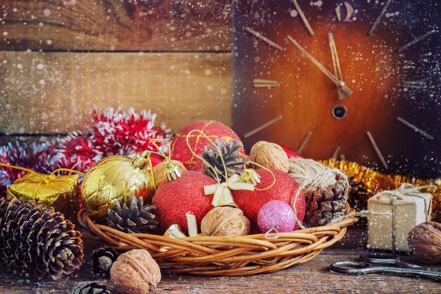 Christmas Composition red and yellow balls, cones,old clock in a basket on wooden .Vintage style. toning