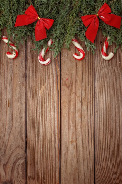 Christmas composition of tree branches, candies and decorations on wooden background. top view. copy space.