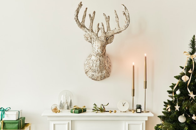 Christmas composition on the white chimney at the living room interior with beautiful decoration. Christmas tree and wreath, candles, stars, light. Copy space.  Template.