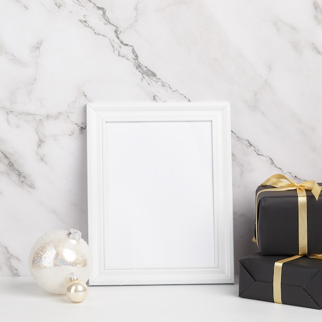 Christmas composition. White framed Christmas decorations and gifts on a marble background