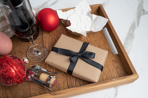 Foto composizione natalizia con vino rosso e formaggio. regalo incartato su vassoio in legno.