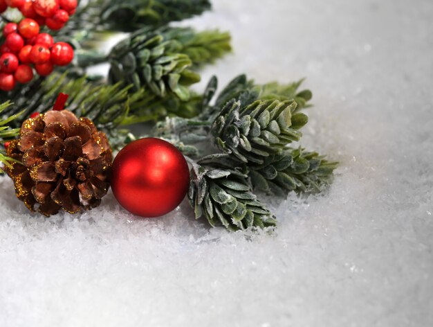 Christmas composition with baubles and fir-tree on snow close-up