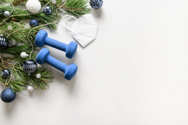 Christmas composition with blue dumbbells, medical mask, and gift