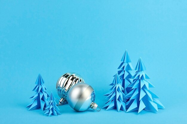 Christmas composition with blue paper fir trees and silver balls