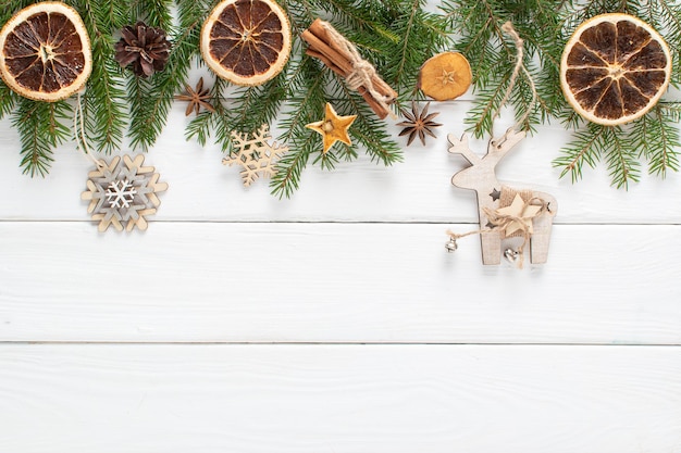 Christmas composition with branches of a Christmas tree and econatural decorations orange cinnamon on a white wooden background