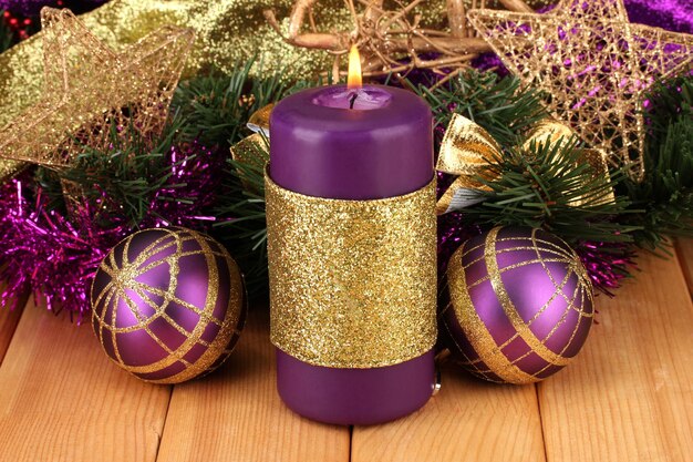 Christmas composition  with candles and decorations in purple and gold colors on wooden background