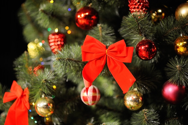 Рождественская композиция с елкой, елочными украшениями и большим красным бантом