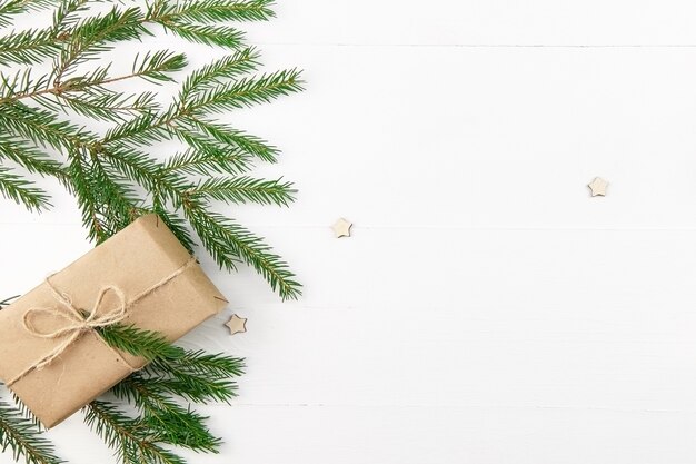 Christmas composition with decorated gift box and fir tree brunches on white