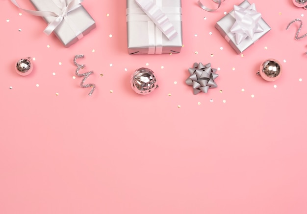 Фото Рождественская композиция с украшениями и подарочной коробке со звездным конфетти на розовой пастели. зима. плоская планировка, вид сверху, copyspace.