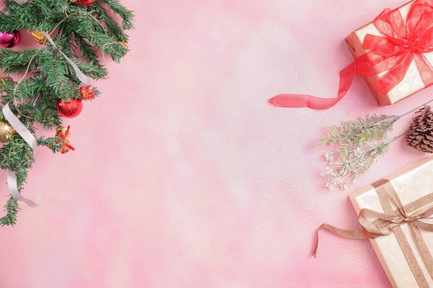 Новогодняя композиция с украшениями и подарочной коробкой с бантами на розовом пастельном фоне. зима, новый год концепция. Плоская планировка, вид сверху, копия пространства.