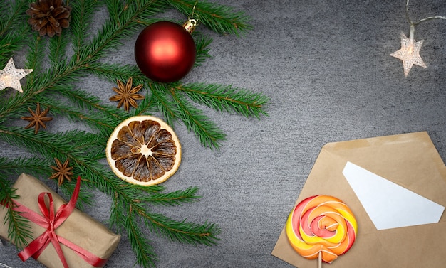 Christmas composition with a fir branch candy a cone an orange an envelope and a gift Lighting