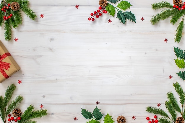 Photo christmas composition with fir branches, candy, gifts, pine cones and stars on light wood