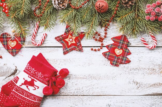 Рождественская композиция с еловыми ветками и красными елочными украшениями на белом деревянном