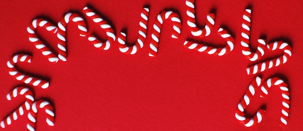 Christmas composition with frame of candy canes on red background Copy space for text banner