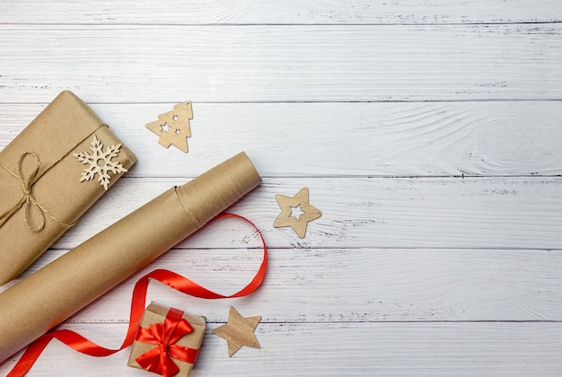 Christmas composition with gifts, craft paper and red ribbon on a white wooden background.