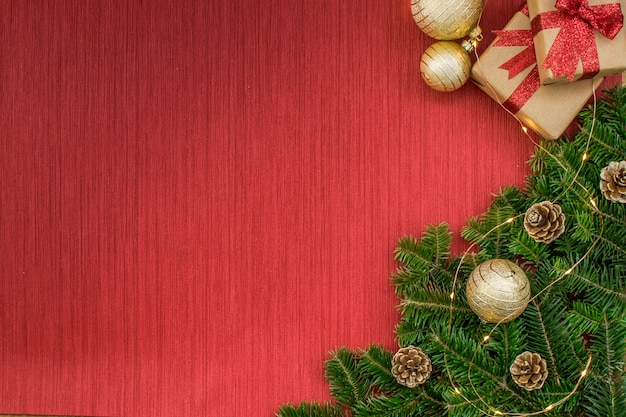 Christmas composition with gifts, golden balls, pine cones, fir branches, lights on a red background