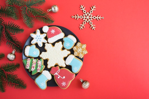 Christmas composition with gingerbread on the black plate on the red background. Top view. Copy space.