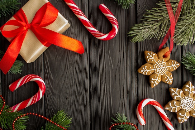 Christmas composition with gingerbread and gift on the black wooden.