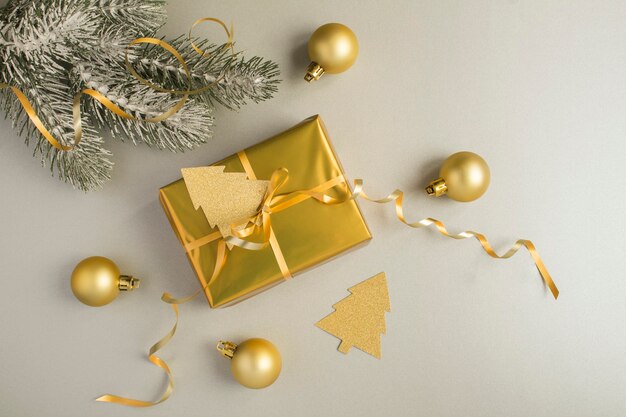 Christmas composition with gold gift box on the gray background. Top view. Copy space.