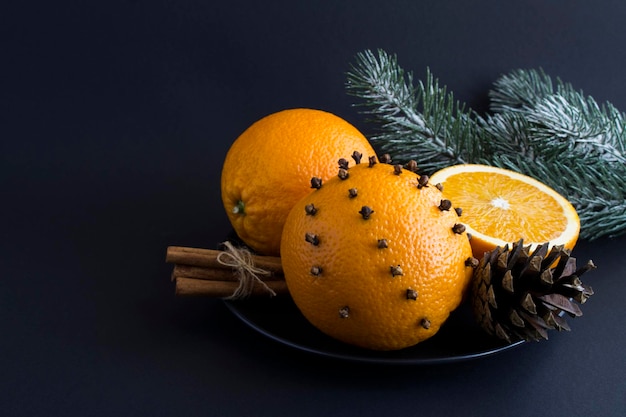 Christmas composition with orange spice cloves and cinnamon on the black plate on the black background Closeup