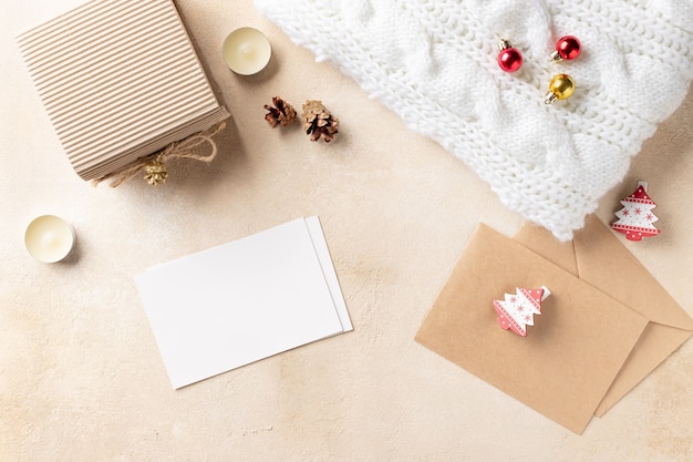 Christmas composition with paper card, gift box, knitted plaid and Christmas decorations