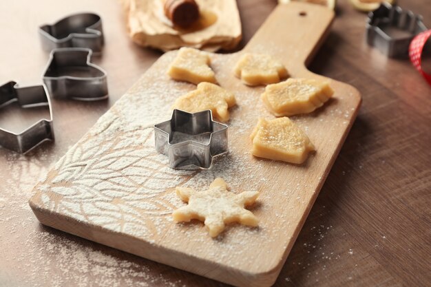 Christmas composition with raw cookies and cutters on wooden table