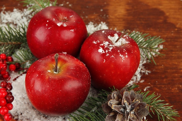 Новогодняя композиция с красными зимними яблоками на деревянных фоне